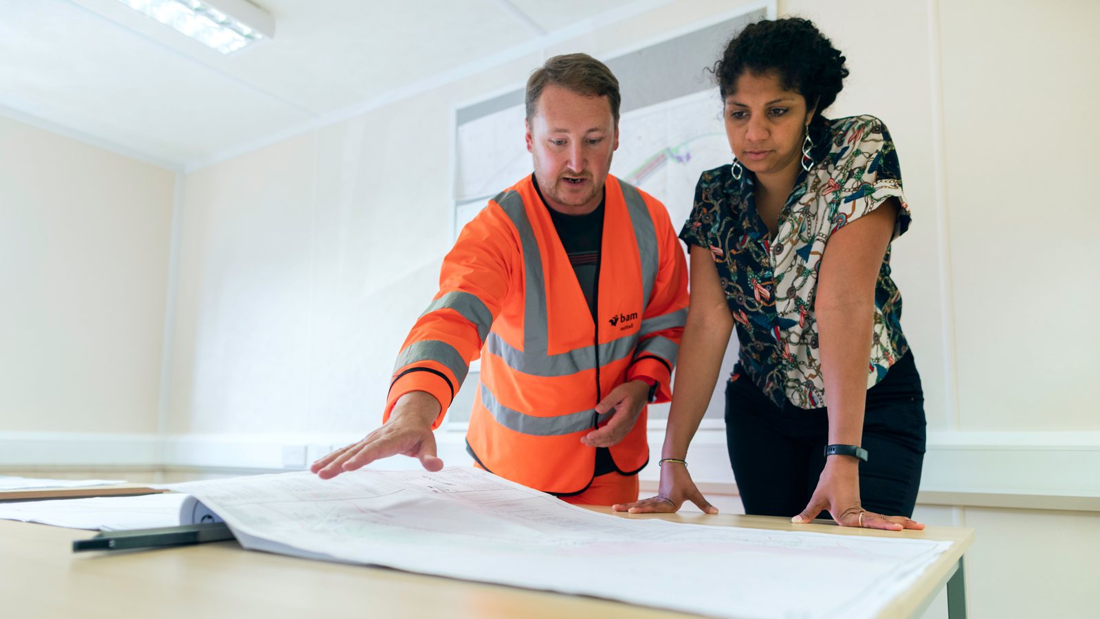 Engineers comparing a construction blueprint and project details