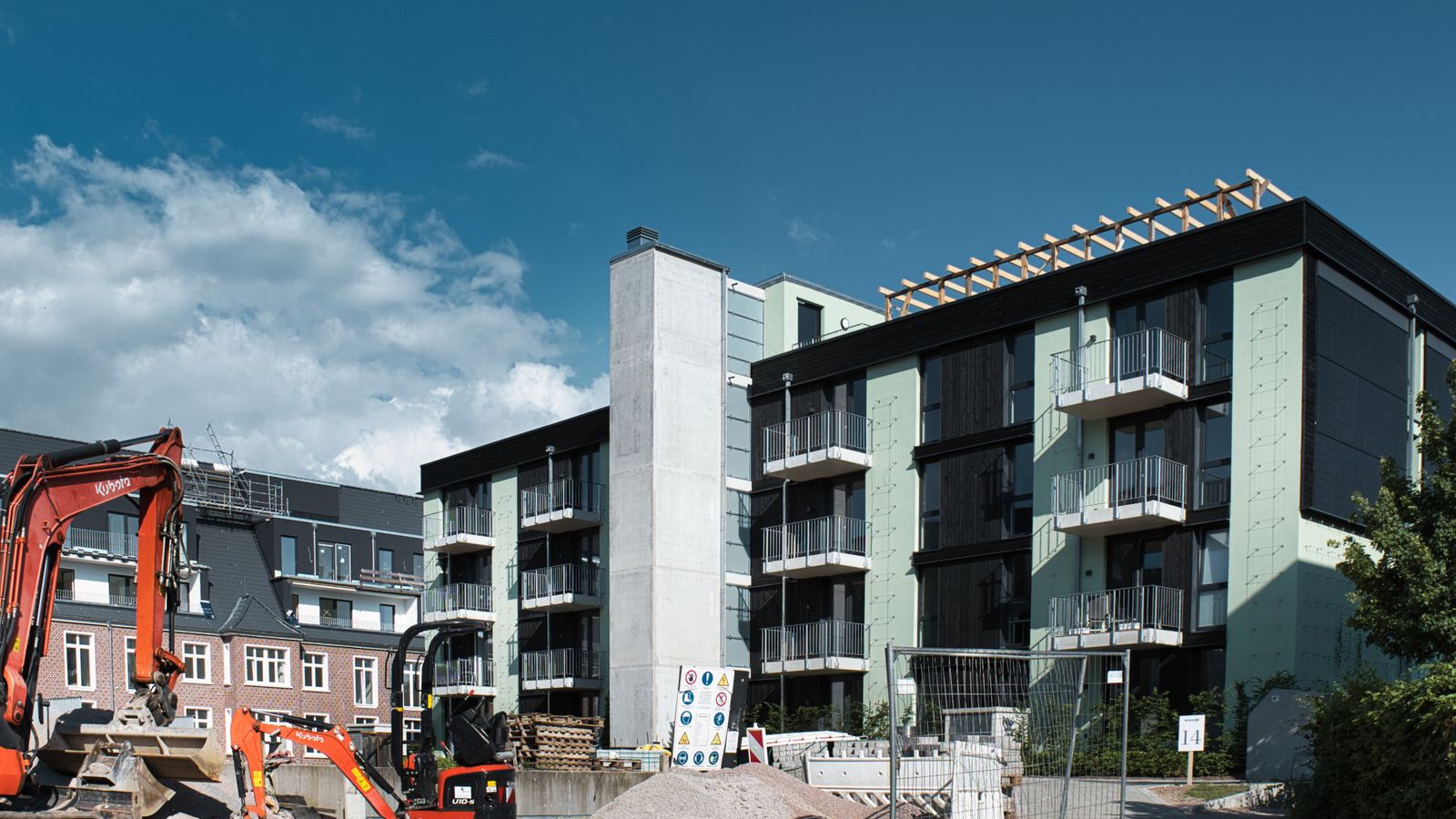 Excavator working beside a new apartment building on a residential infill site