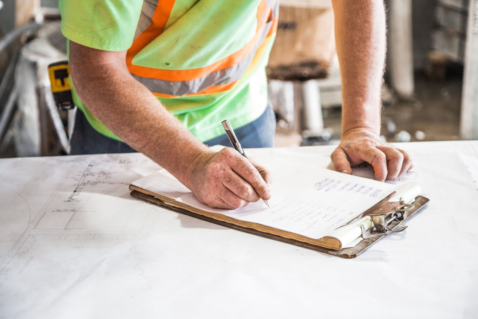 Construction professional recording site decisions on a clipboard